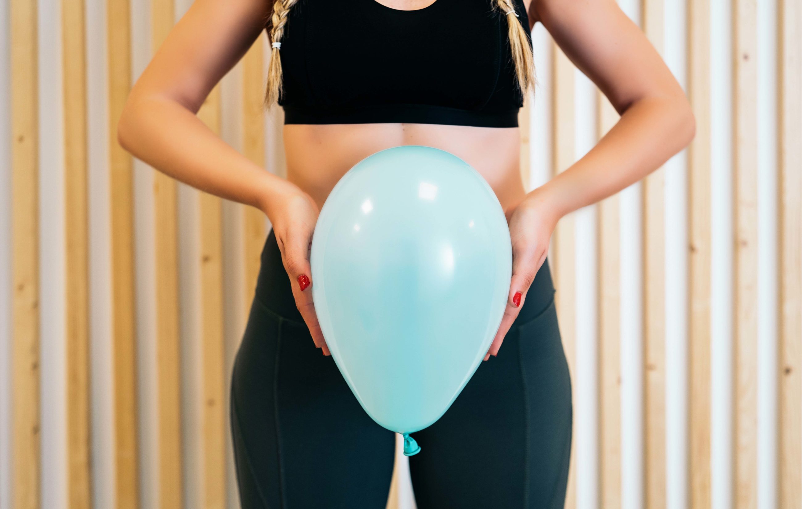 Close up of a young woman holding a balloon to explain the diaphragm zones, core and pelvic floor. Pelvic floor exercises explained