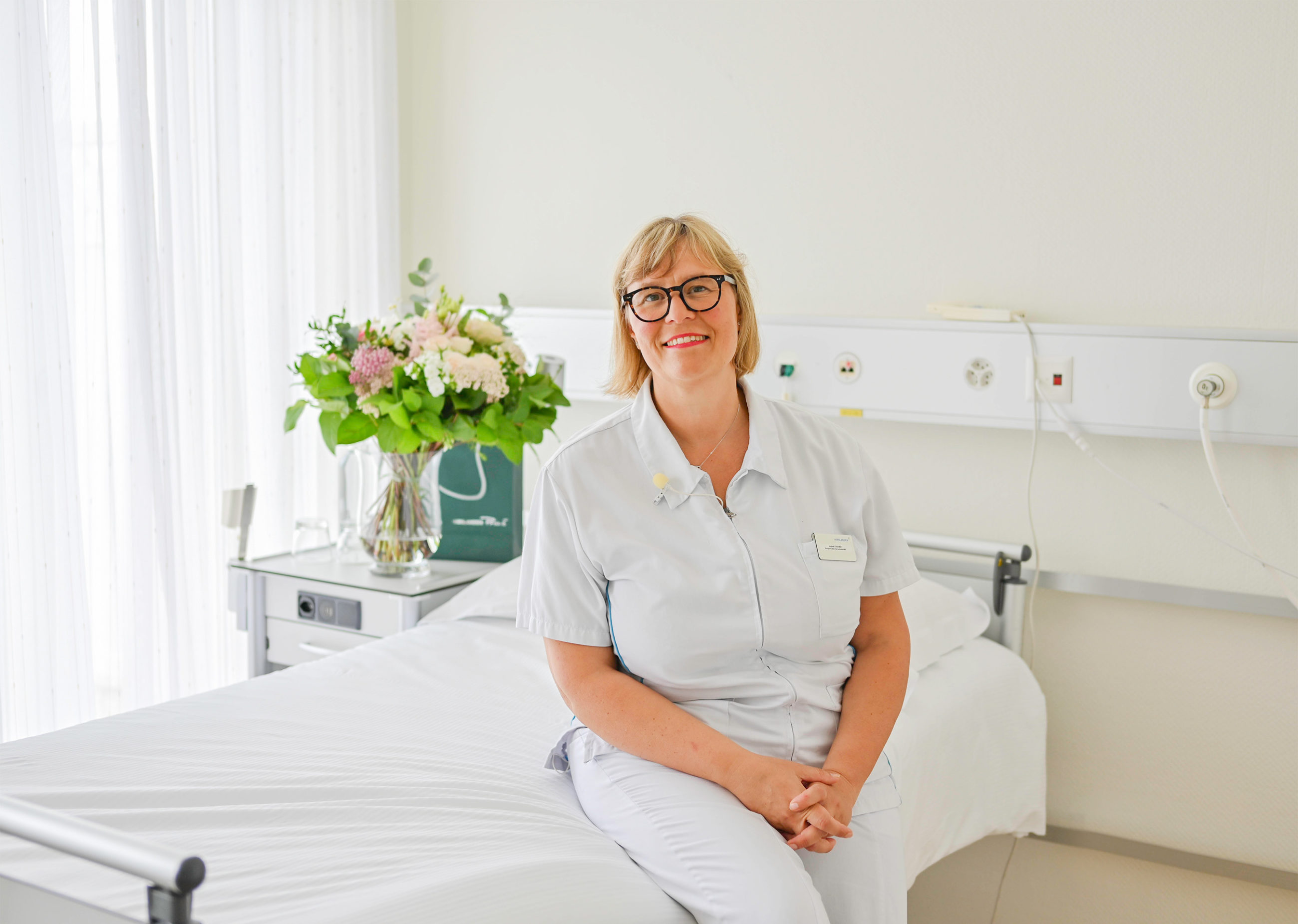 Isabelle, sage-femme responsable de la maternité Cecil Lausanne assise sur le lit d'une chambre.